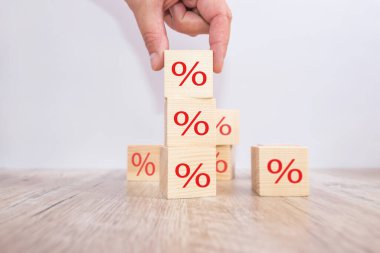 Faiz oranı finansal ve ipotek oranları kavramı. Elle yerleştirilen tahta küp bloğu üste yükseltiliyor ve simge yüzdesi sembolü yukarı doğru gösteriliyor