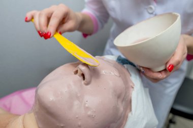 Güzellik Salonu genç bir kadın yüzü Alginic bir maske uygulamak güzellik uzmanı yordam temizlik ve cilt nemlendirici için. Kozmetik ve profesyonel Cilt Bakımı