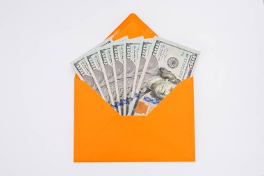 Beyaz arka planda turuncu bir zarfın içinde dolar. İçinde dolar banknotları olan açık bir zarf. Zenginlik ve gelir kavramı.