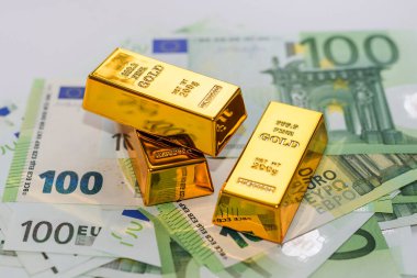 Gold bars on the background of 100 euro banknotes close-up