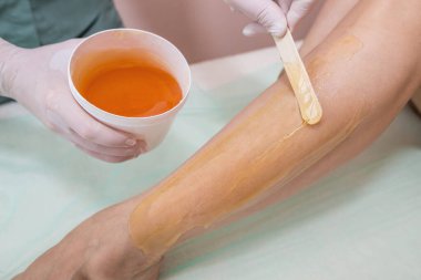 Hair removal at spa studio. Woman legs wax with sugaring. Hot sugar.