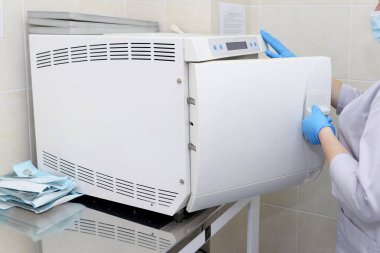 Otoklavda tıbbi aletlerin sterilize edilmesi. Diş hekimliği. Bir kadın otoklavda tıbbi aletleri sterilize ediyor..