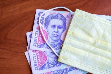 200 Hryvnia banknotları ve tıbbi maskeler. Ekonomik kriz. Ukrayna parası, koronavirüs konsepti