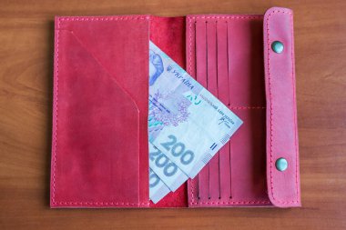 Bir kadının cüzdanında 200 Hryvnia banknotu. Masada hryvnias kırmızı cüzdan