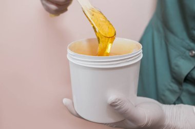 Tahta bir çubukta tüy dökmek için sıvı sarı şeker yapıştırıcısı ya da balmumu kabın içinde şeker yapıştırıcısı.