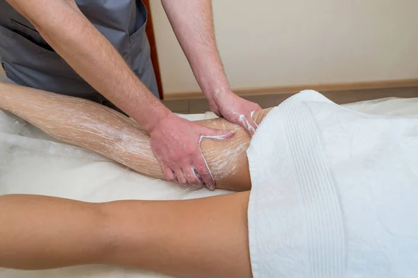 foot scrub in spa salon.Male massage therapist applies cleansing scrub on young girl\'s feet. Body care concept.