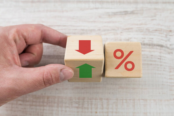Концепция процентной ставки по финансовым и ипотечным ставкам. Рука переворачивает стрелку куба вниз, чтобы вверх
