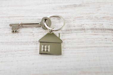 Ev anahtarı ve anahtarlık ahşap tahtaların üzerinde. Gayrimenkul, ipotek, taşınma ya da ev kiralama kavramı.