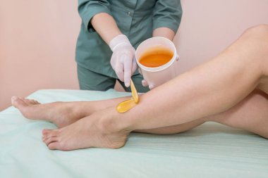 Spa lüks stüdyosunda saç kesimi. Kadın bacakları şekerle ağda yapıyor. Sıcak şeker.