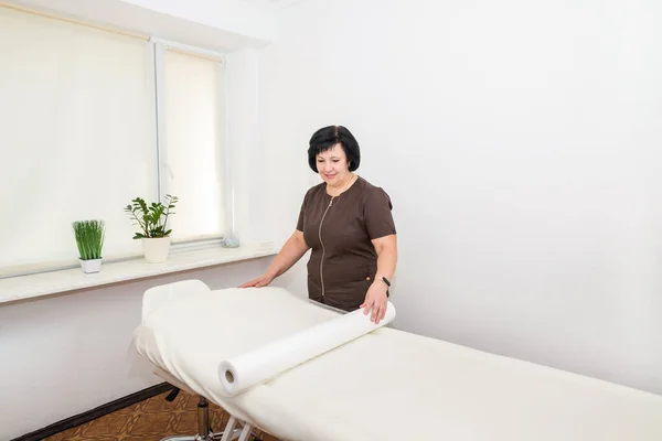 Masseuse Bij Massagetafel Vrouwelijke Masseuse Met Een Rol Wegwerphanddoek Spa — Stockfoto