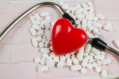 Taştan, vitaminden, haplardan, steteskoptan yapılmış kırmızı bir kalbin yakın plan fotoğrafı..