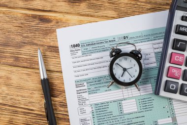 Üst düzey vergiler, hesap makinesi ve tahta bir masa üzerindeki kalemle 1040 şeklindedir. finansal belge.