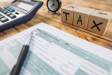 Tahta arka planda hesap makinesi ve aksesuarları olan 1040 vergi formu. Vergilendirme kavramı.