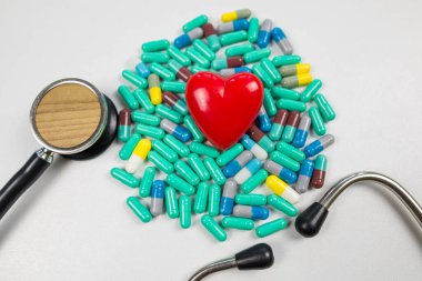Steteskoplu hap kapsülleri ve mavi arka planda kırmızı bir kalp. tıbbi konsept