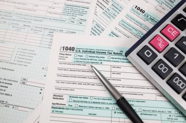 Hesap makinesi ve kalemle 1040 vergi formunu kapat