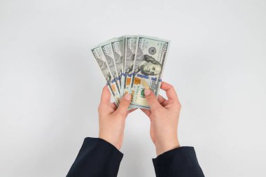 Beyaz ellerde izole edilmiş kadın ellerindeki dolarların üst görünümü.