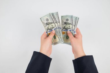 Beyaz ellerde izole edilmiş kadın ellerindeki dolarların üst görünümü.