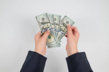 Beyaz ellerde izole edilmiş kadın ellerindeki dolarların üst görünümü.