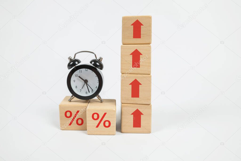 interest rate. inflation, risk management, financial business concept. Growth symbol percent icon and up arrow on a wooden cubic block and a small alarm clock.