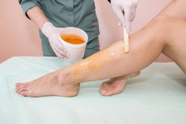 Kozmetik bilimci ve müşteri, spa merkezinde sıvı şekerle bacakları tükendi.