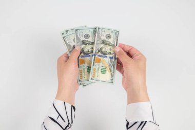 Beyaz ellerde izole edilmiş kadın ellerindeki dolarların üst görünümü.