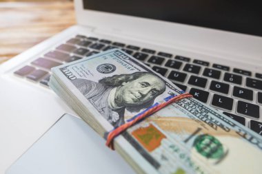 Bir dizüstü bilgisayarın klavyesine yığınla doların yakın plan görüntüsü.