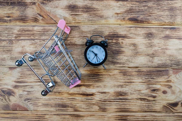 小さな黒い目覚まし時計とおもちゃのショッピングカート ショッピングカートの時計 時間の不足 時間の無駄 ショッピング時間 — ストック写真