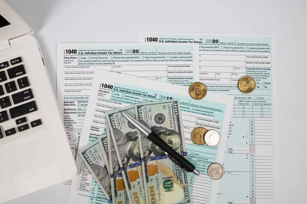 1040种税单的顶部视图 带有美元笔记本电脑和白色背景的钢笔 纳税时间 财务文件 — 图库照片