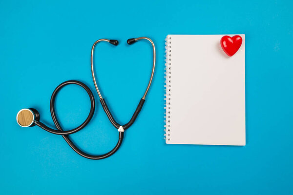 Blank notepad ,stethoscope and red heart on blue. View from above. Place for text. medical concept
