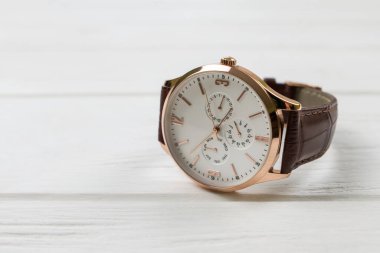 Close-up of a men's wrist watch on a white wooden background with copy space. Mechanical wrist watch with a brown strap.
