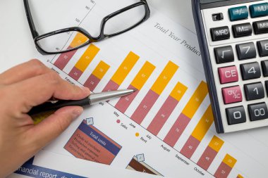 Çizelgeye işaret eden bir kadının yakın çekimi. İstatistiksel verileri karşılaştırır, grafik grafiklerindeki değerleri inceler, eğilimlerin örüntülerini analiz eder, notlar alır