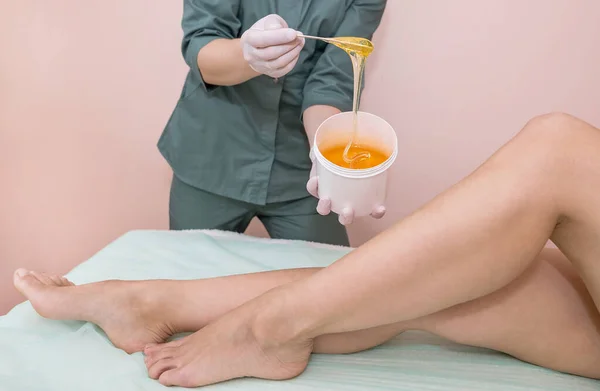 Sugaring legs in the spa. Skin and body care. The concept of waxing and sugaring.