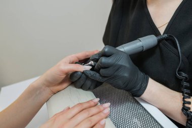 Güzellik salonunda manikür, değirmen makasıyla tırnak temizleme. Manikürcü müşterinin tırnaklarını törpülüyor, kapat. Çivi levhasını değirmen makinesiyle sökmek.