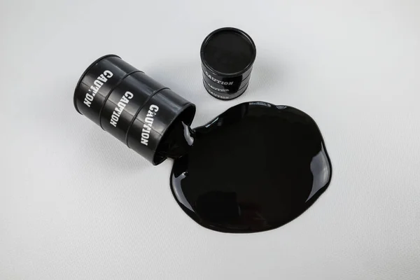 油是从一个黑色的油桶里倒出来的 被白色隔离了白色上有油的玩具桶 — 图库照片