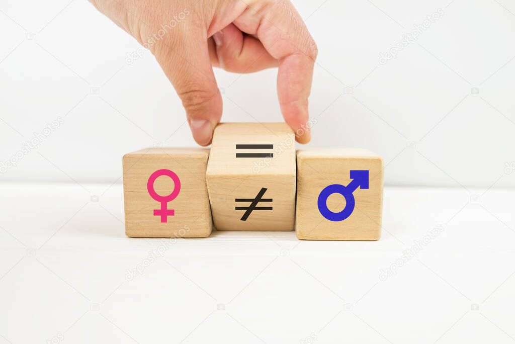 Gender equality symbol. The hand rotates the cube and changes the inequality sign to an equal sign between the symbols of men and women. Space for copy.