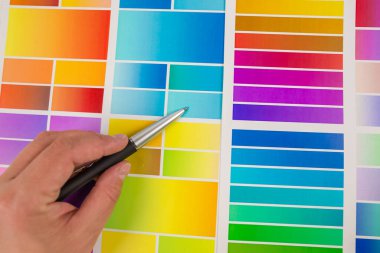 Yaratıcı insanlar için bir işyeri. Renk paletiyle çalışan genç bir bayan tasarımcının yakın çekimi. Bir kadının eli kalem kullanarak bir tasarım projesi için renk örnekleri seçer.