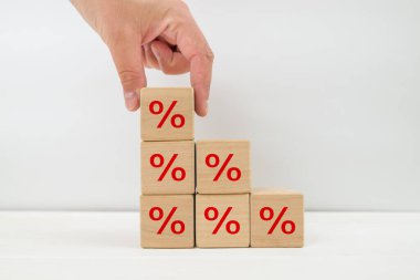 Faiz oranı finansal ve ipotek oranları kavramı. Elle yerleştirilen tahta küp bloğu üste yükseltiliyor ve simge yüzdesi sembolü yukarı doğru gösteriliyor