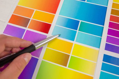 Yaratıcı insanlar için bir işyeri. Renk paletiyle çalışan genç bir bayan tasarımcının yakın çekimi. Bir kadının eli kalem kullanarak bir tasarım projesi için renk örnekleri seçer.