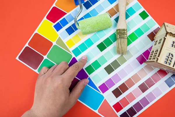 A woman\'s hand chooses a color on a color palette. The concept of repairing an apartment or house. Choice of color for wall painting.