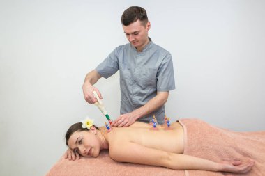 Bardak masajı. Elektrik süpürgesine masaj yap. Spa salonunda sırtüstü uzanmış bir adamın yakın çekimi. Tedavi ve kozmetolojide vakum bankaları. Süpürge terapisi..