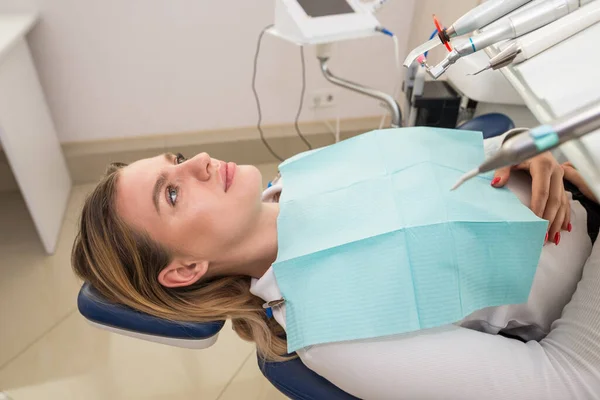female patient lies in a dental chair waiting for tooth treatment