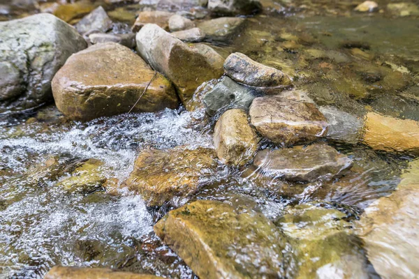 Close-up of mountain water with stones in the river.mountain river rapids with fast water and large rocky boulders in the water and the massive rocks