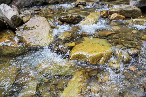 Close-up of mountain water with stones in the river.mountain river rapids with fast water and large rocky boulders in the water and the massive rocks