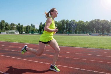 Sports woman runs in the stadium.