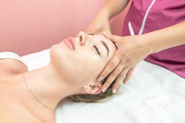 Beautiful girl doing facial massage in beauty clinic