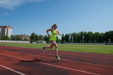 Sports woman runs in the stadium.