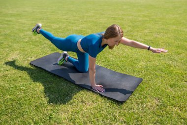 Fit woman doing stretching on mat at outdoor in city stadium. concept of healthy lifestyle muscle flexibility