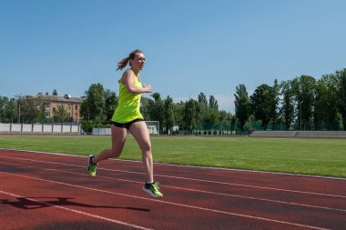 Sports woman runs in the stadium.