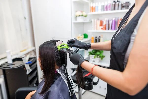 Hairdresser using a hair straightened to straighten the hair. Hair stylist working on a woman\'s hair style at salon.Hair care. Beautiful, attractive woman in a beauty salon.