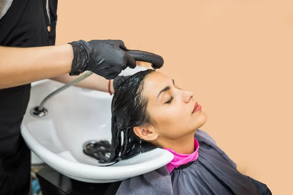 female client washes hair in salon, professional hairdresser washes head of female client with water and shampoo treatment, hairstyle beauty hair care, fashion service.